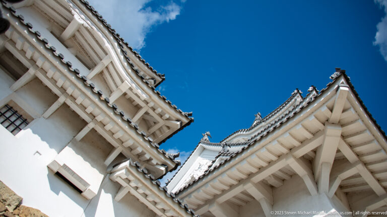 Low-angle view of white castle towers and layered eaves.