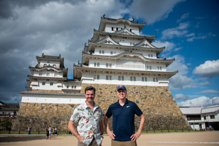 Two visitors standing before Himeji Castle's main keep.