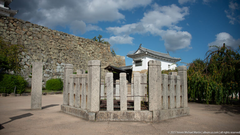 Stone monument enclosed by a fence inside Himeji Castle grounds.
