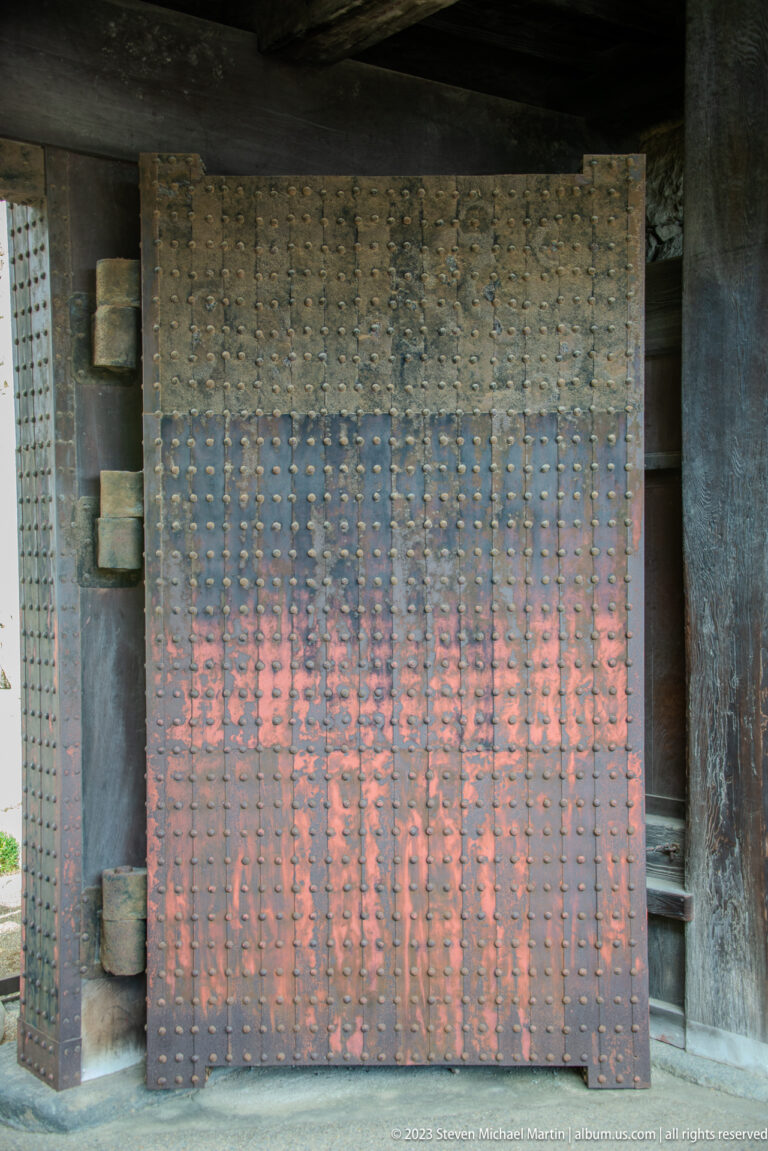 Large wooden castle gate covered with rows of iron studs and heavy hinges.