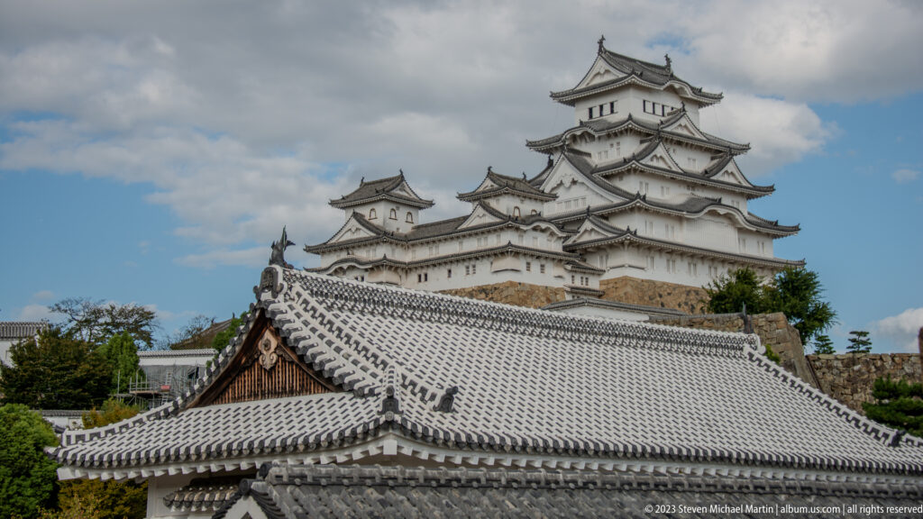Himeji Castle’s main keep rising behind a broad gray-tiled foreground roof.