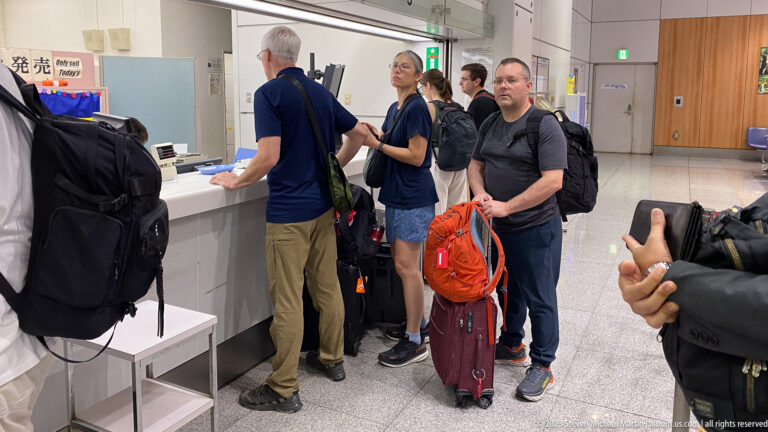 Group of travelers with backpacks and rolling luggage standing at a service counter inside Himeji Station.