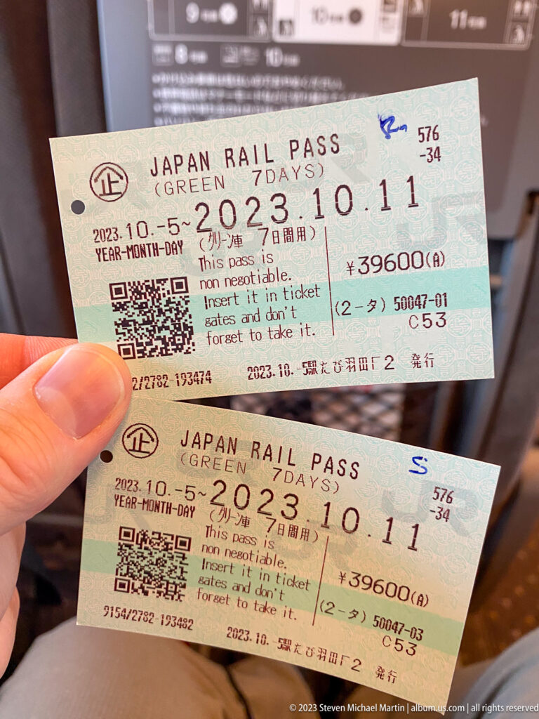 Hand holding two seven-day Japan Rail Pass tickets dated October 2023.