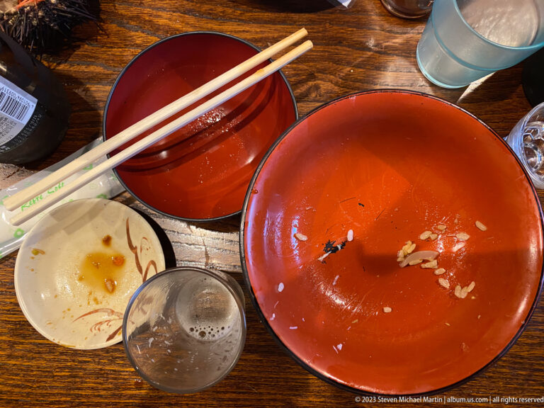 Empty red lacquer bowls, chopsticks, glassware, and a small dish after a meal.