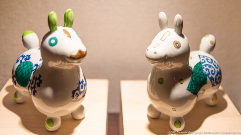Two white ceramic rabbit figures decorated with blue, green, turquoise, and orange motifs.