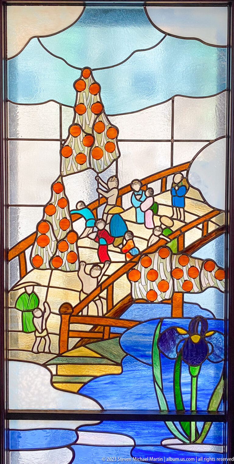Stained-glass scene of workers, stacked baskets, a wooden platform, and a boat on blue water.
