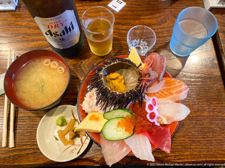 Assorted sashimi, octopus, salmon roe, and sea urchin in its shell with soup and drinks.