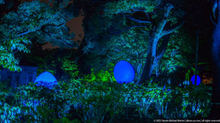 Several blue glowing responsive ovoid forms among shrubs and mature trees.