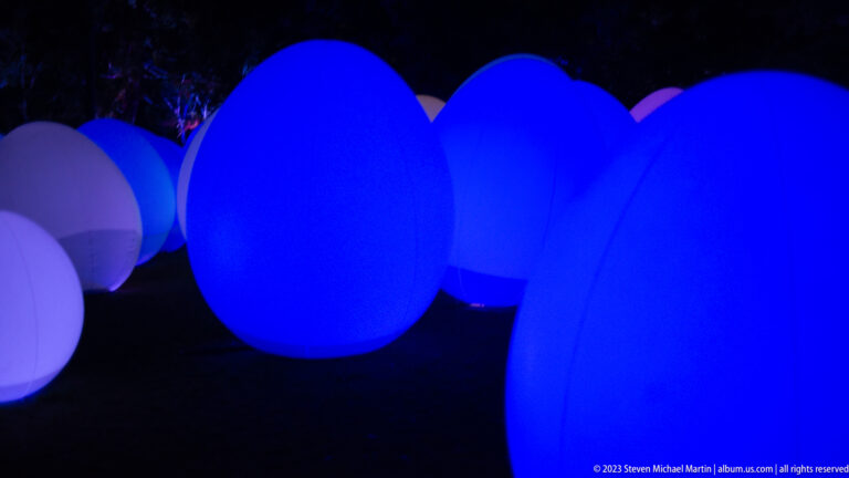 Close view of overlapping blue glowing responsive ovoid forms with pale ovoids behind.