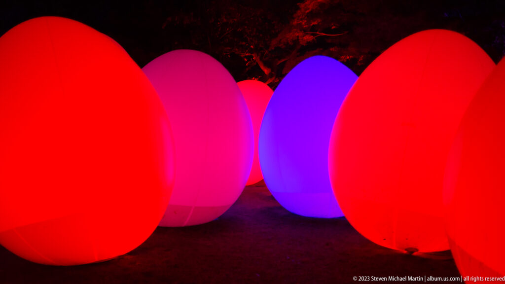 Large red glowing responsive ovoid forms with violet and pink lights behind.