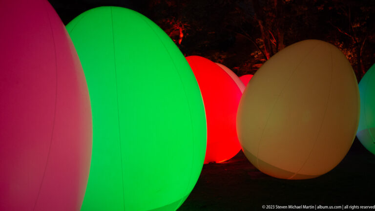 Close grouping of green, red, cream, and pale pink glowing responsive ovoid forms.