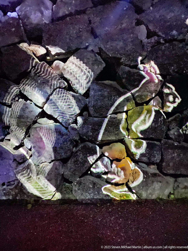 Stylized human figures projected across irregular dark paving stones.