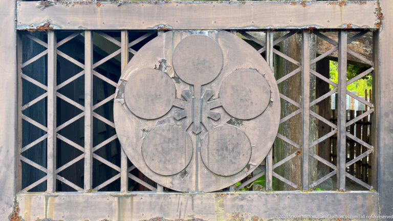 Large circular Japanese crest with four rounded lobes mounted on a geometric wooden lattice.