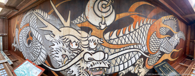 Large black, white, and orange dragon mural covering a wooden interior wall.