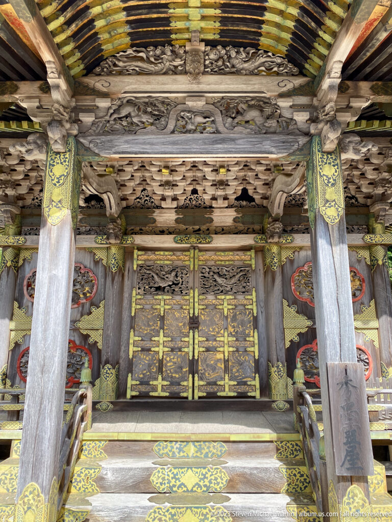 Ornate Tokugawa mausoleum façade with gilded doors, carved beams, and painted brackets.