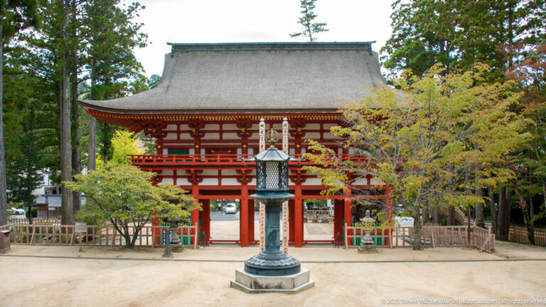 Vermilion Chūmon gate with a large tiled roof and bronze lantern centered in the approach.