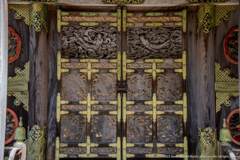 Decorated carved shrine doors with gilded hardware.