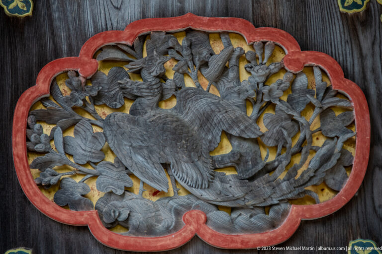 Carved bird relief in painted frame.