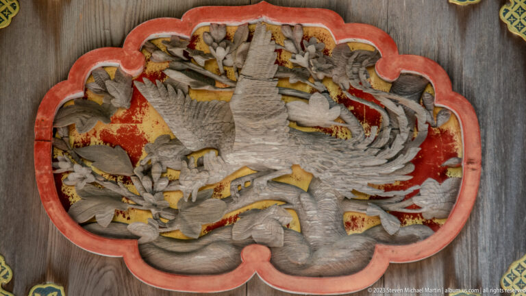 Phoenix wood carving in painted frame.