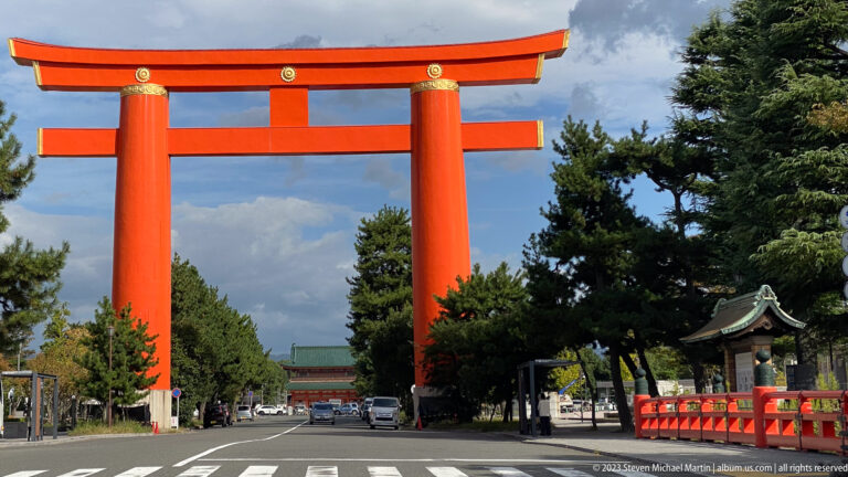 Monumental vermilion Otorii of Heian Jingu spanning Jingu-michi, with shrine buildings visible beyond.