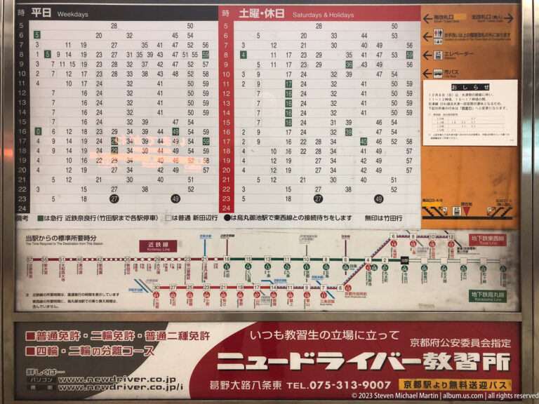 Printed timetable and route information board in its surrounding Kyoto setting.