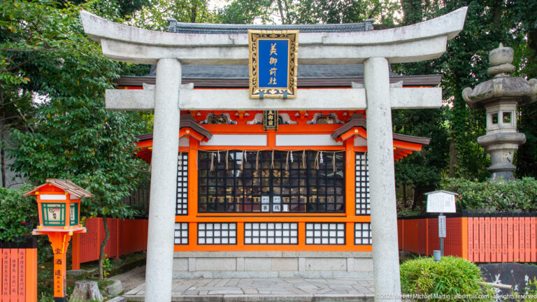Granite torii framing a vermilion shrine with stone lanterns.