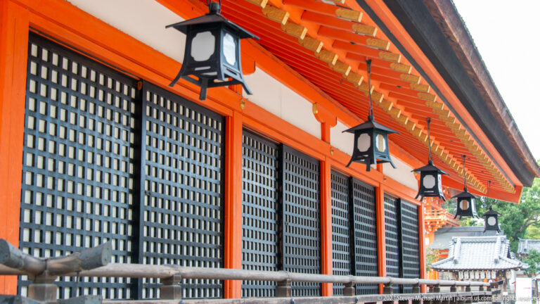 Long shrine exterior with repeating lanterns beneath vermilion eaves.