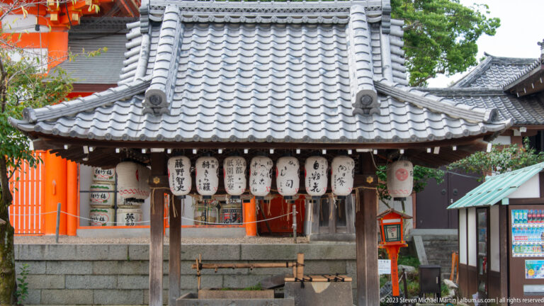 Small pavilion displaying rows of inscribed white paper lanterns.