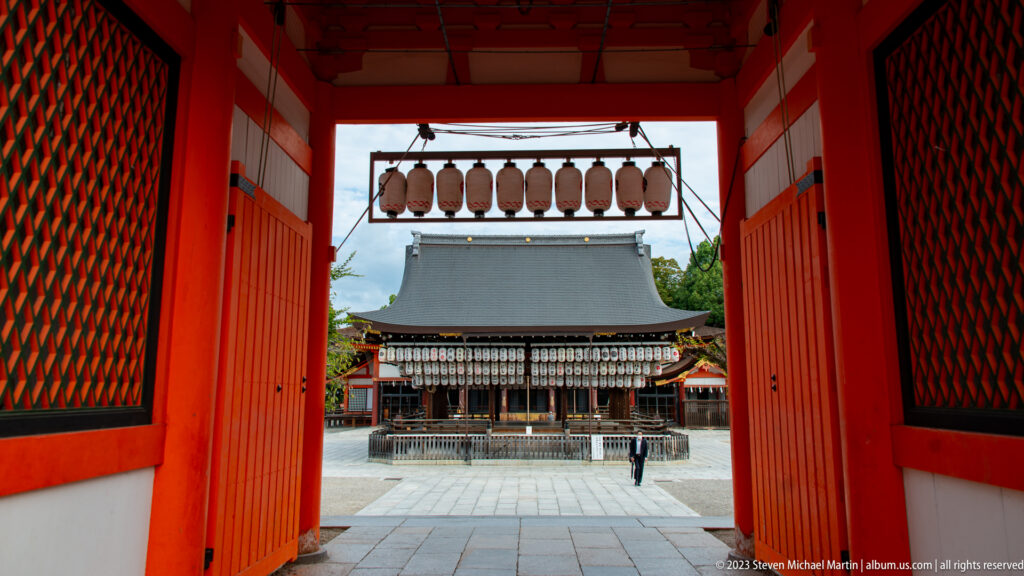 Lantern-covered Buden framed through a vermilion shrine gateway.