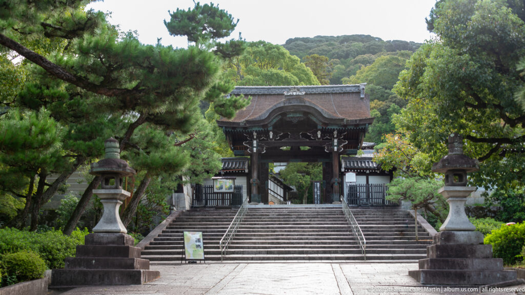 Broad stone stairway leading to a large timber temple gate.