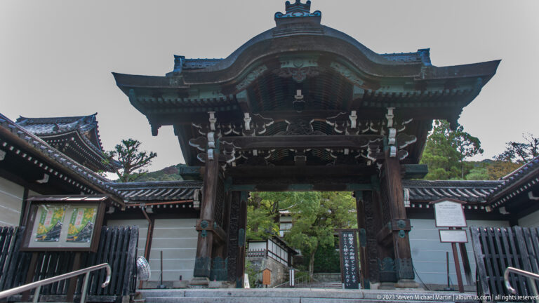 Ornate wooden temple gate with curved roof and deep eaves.