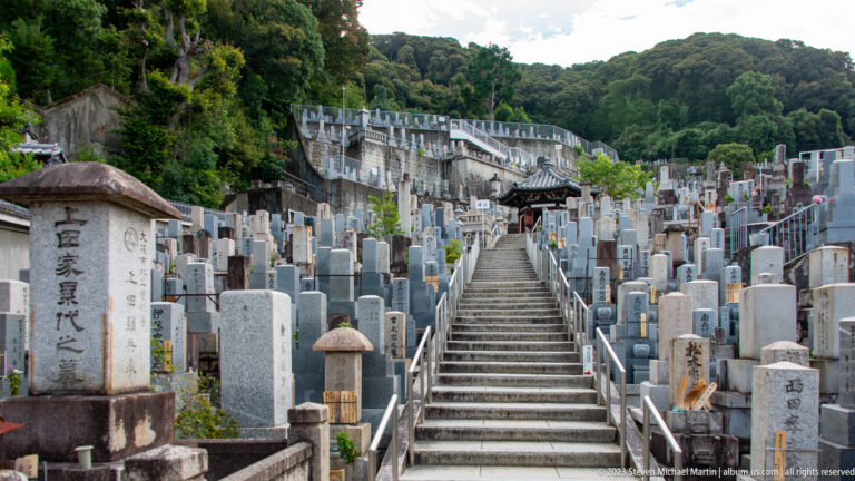 Central stone stairway climbing through densely arranged graves in Higashi Otani Cemetery.