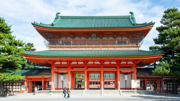 Vermilion Otenmon gate of Heian Jingu with a broad green-tiled roof in its surrounding Kyoto setting.