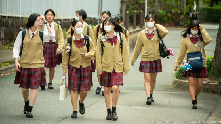 Group of students in school uniforms walking outdoors in its surrounding Kyoto setting.
