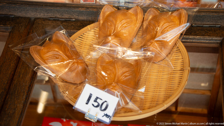 Fox-shaped pastries displayed in a basket in its surrounding Kyoto setting.