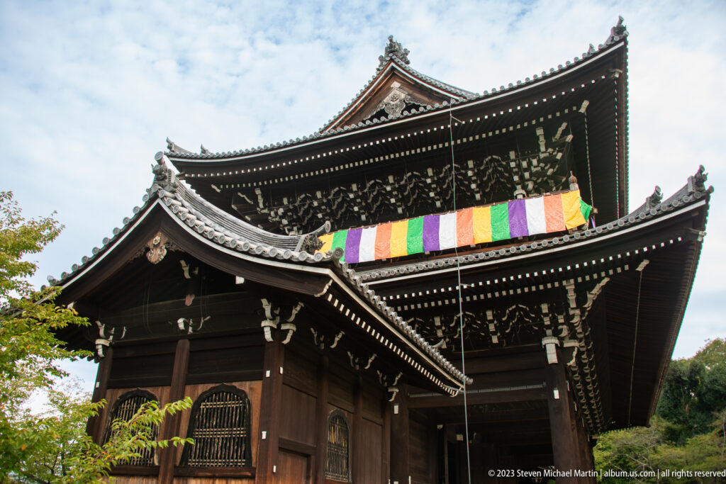 Low-angle view of Chion-in's massive two-story Sanmon gate with dark timber, tiled roofs, and five-colored cloths.