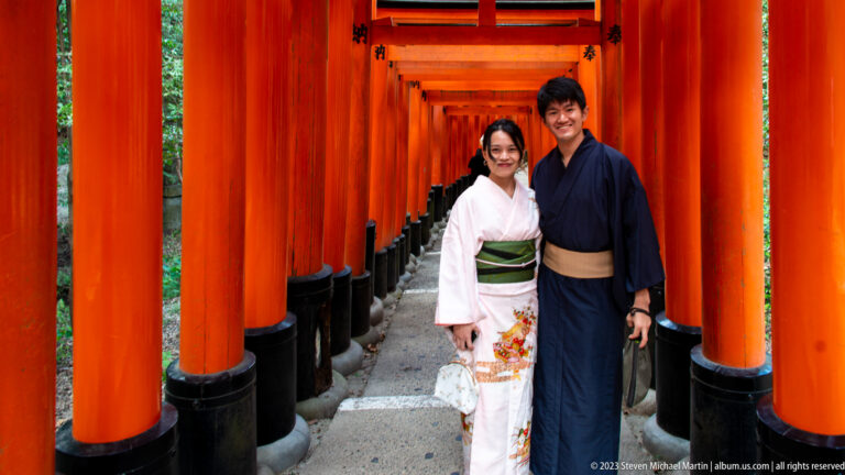 Full-length portrait of a couple framed by rows of vermilion torii.