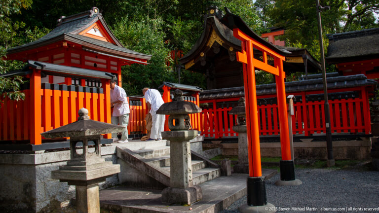 Small shrine beyond a vermilion torii and stone lanterns.
