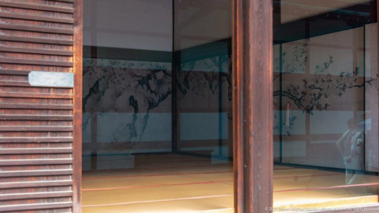 Monochrome landscape painted on sliding interior panels, seen through reflective glass.