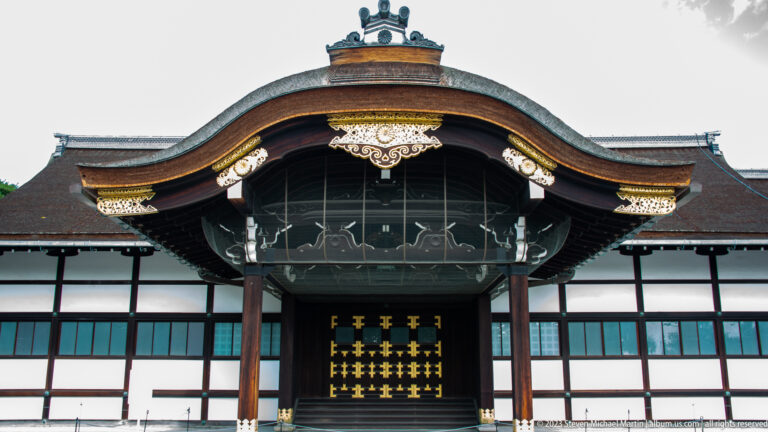 Symmetrical palace façade with curved gable, dark timber framing, and closed ceremonial doors.