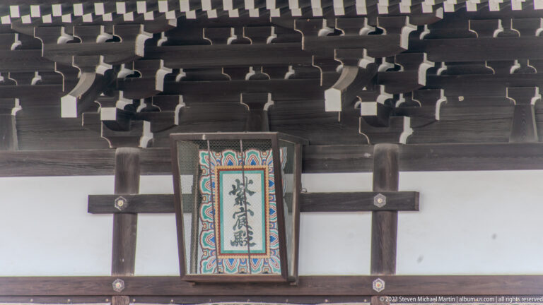 Close-up of a multicolored framed calligraphic plaque on a palace hall.