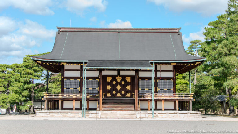 Front view of a raised palace hall with broad roof, central stairs, and ornate doors.