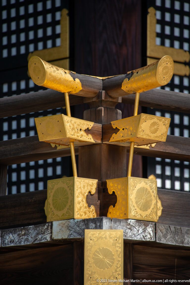 Close-up of an elaborate gilded palace fitting with floral roundels and curved metal arms.
