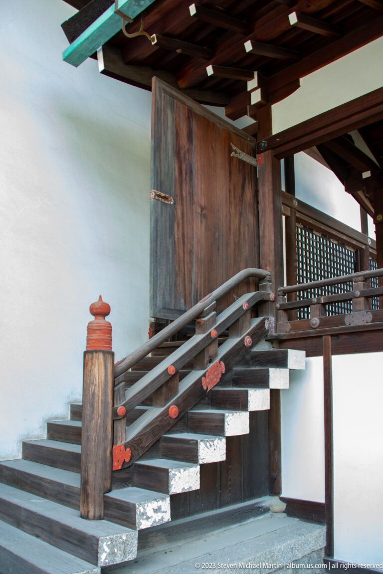 Short wooden stair with dark railings leading to an open palace doorway.
