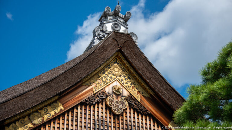 Low-angle close-up of an ornate palace gable with gold scrollwork and roof crest.