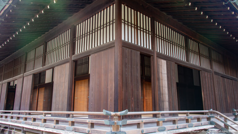 Corner of a timber palace building with lattice transoms and raised veranda.
