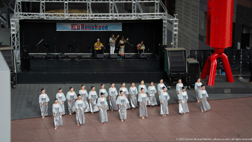 Group of dancers in pale costumes performing before a stage at Kyoto Station.