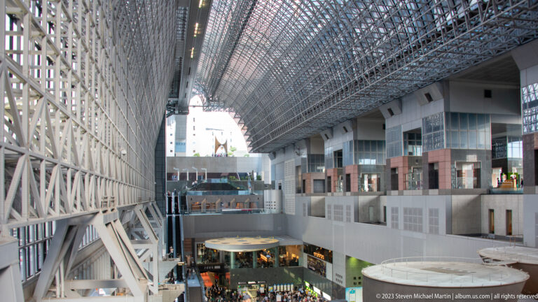 Interior overview of Kyoto Station showing the central atrium beneath an exposed steel-and-glass roof.