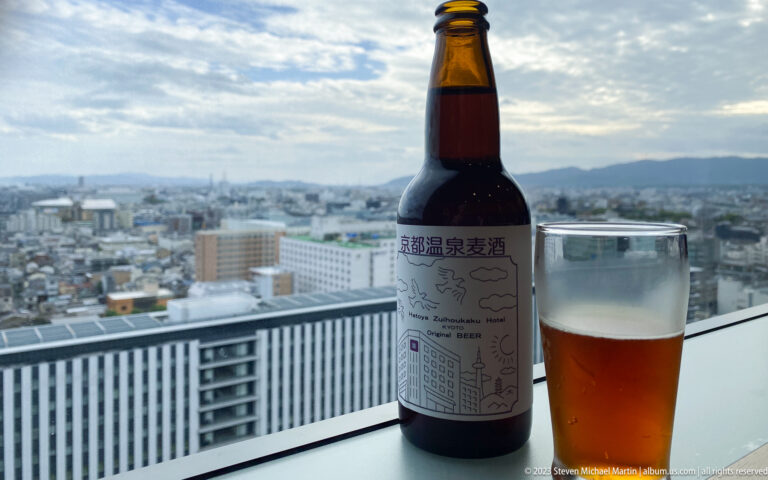 Bottle of beer and filled glass overlooking Kyoto skyline.