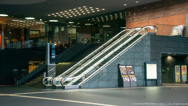 Paired escalators rising through Kyoto Station interior.